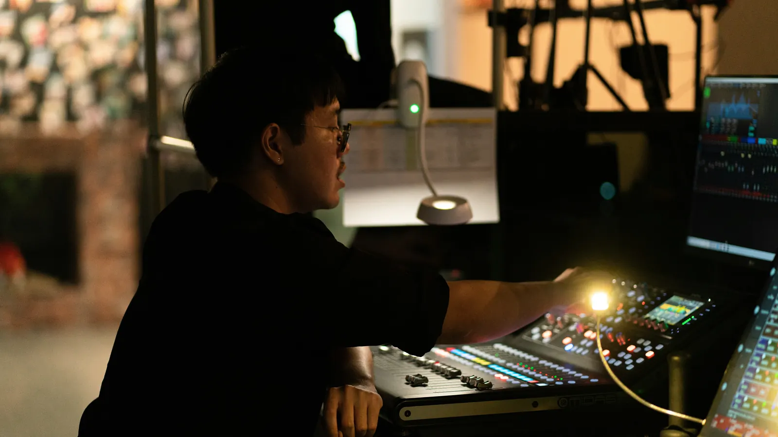 A person working at a lit mixing desk in a dark room